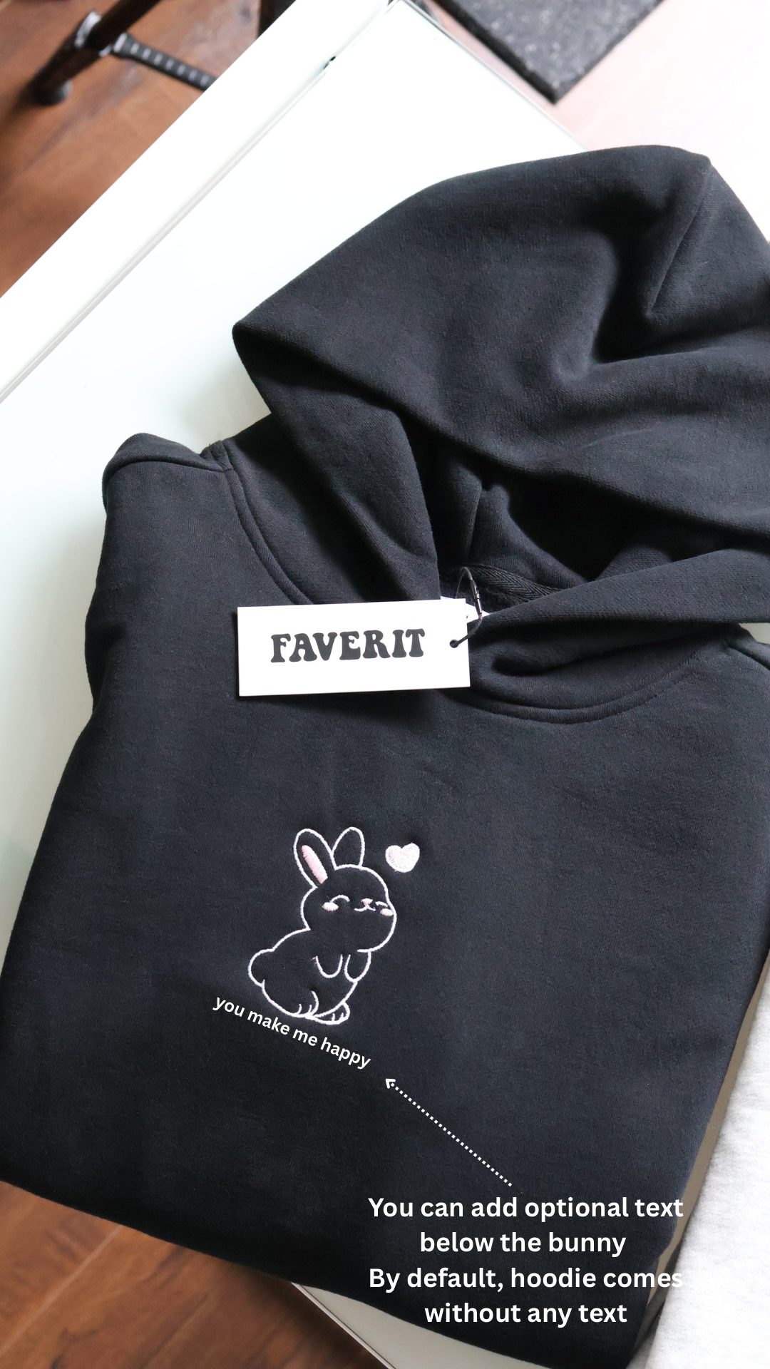 Black hoodie with a bunny design and 'FAVERIT' brand tag on a wooden surface.