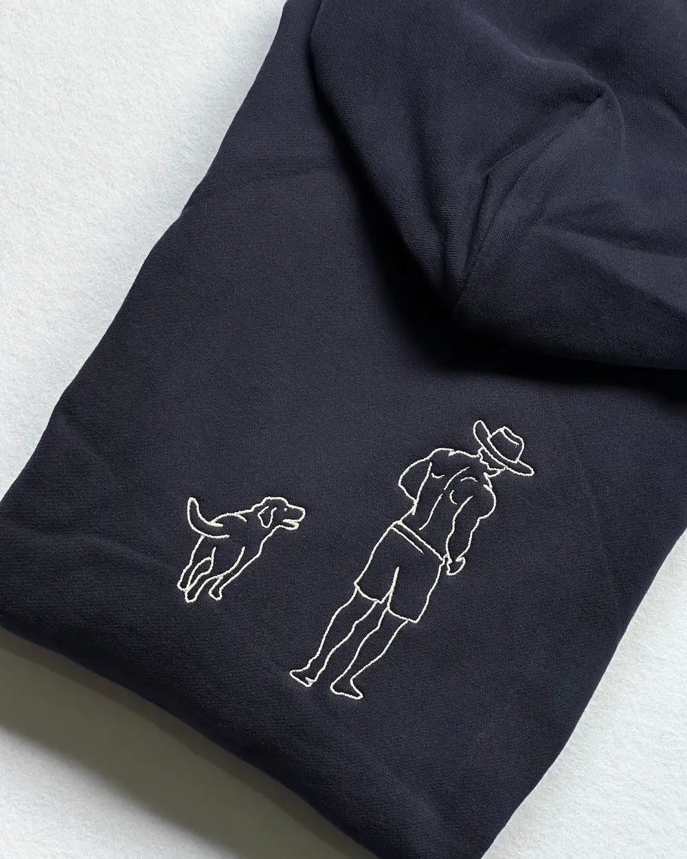 Custom pet embroidery hoodie Australia — personalised dog and owner portrait line art on navy 380GSM cotton hoodie, embroidered in Melbourne